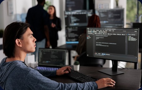 An intern writing code at a multi-monitor workstation