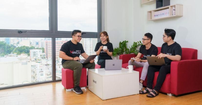 Team members chatting with laptops in a bright office lounge